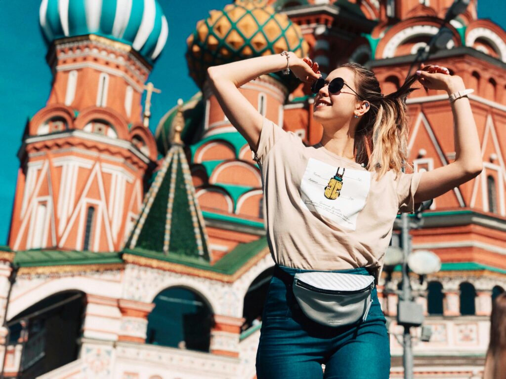 Happy woman posing in front of Saint Basil's Cathedral, Moscow, on a sunny day.