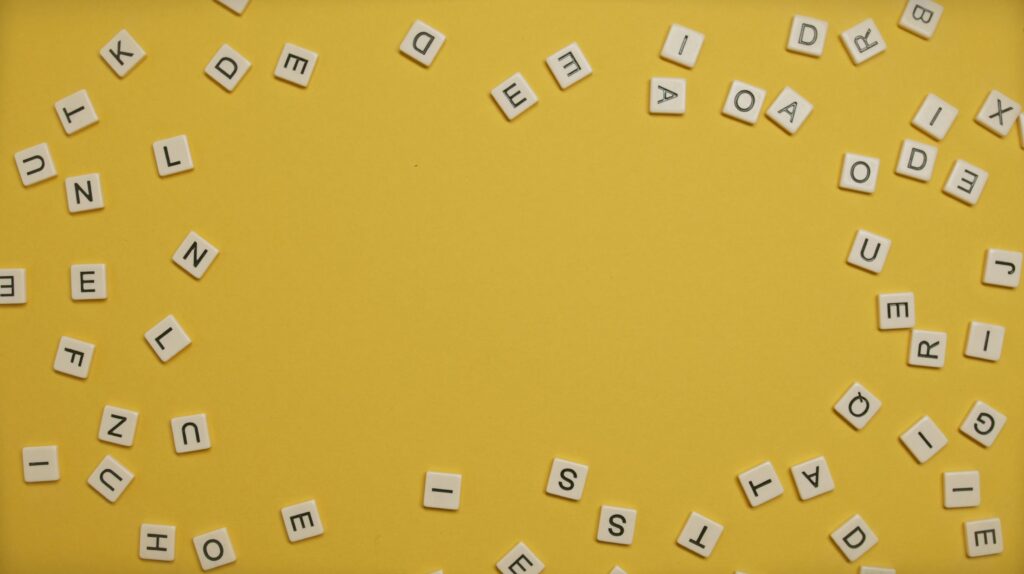 Scattered alphabet letters forming a circular pattern on a bright yellow background.
